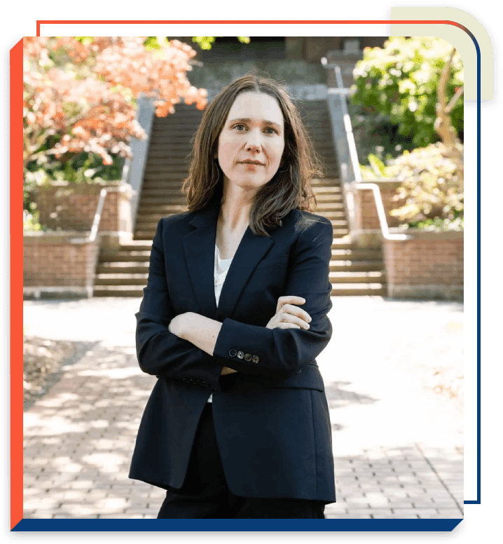 A woman in a suit standing on the sidewalk.
