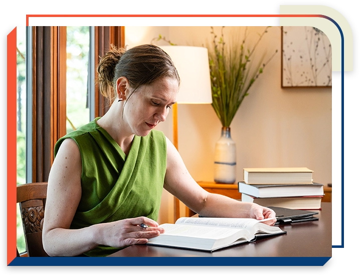8 A woman sitting at a table reading a book.